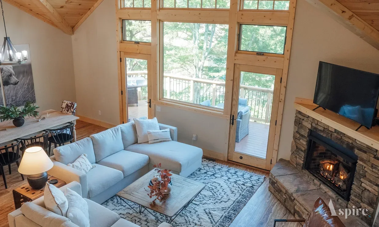 Vaulted timber living room with a lit stone fireplace and mountain views