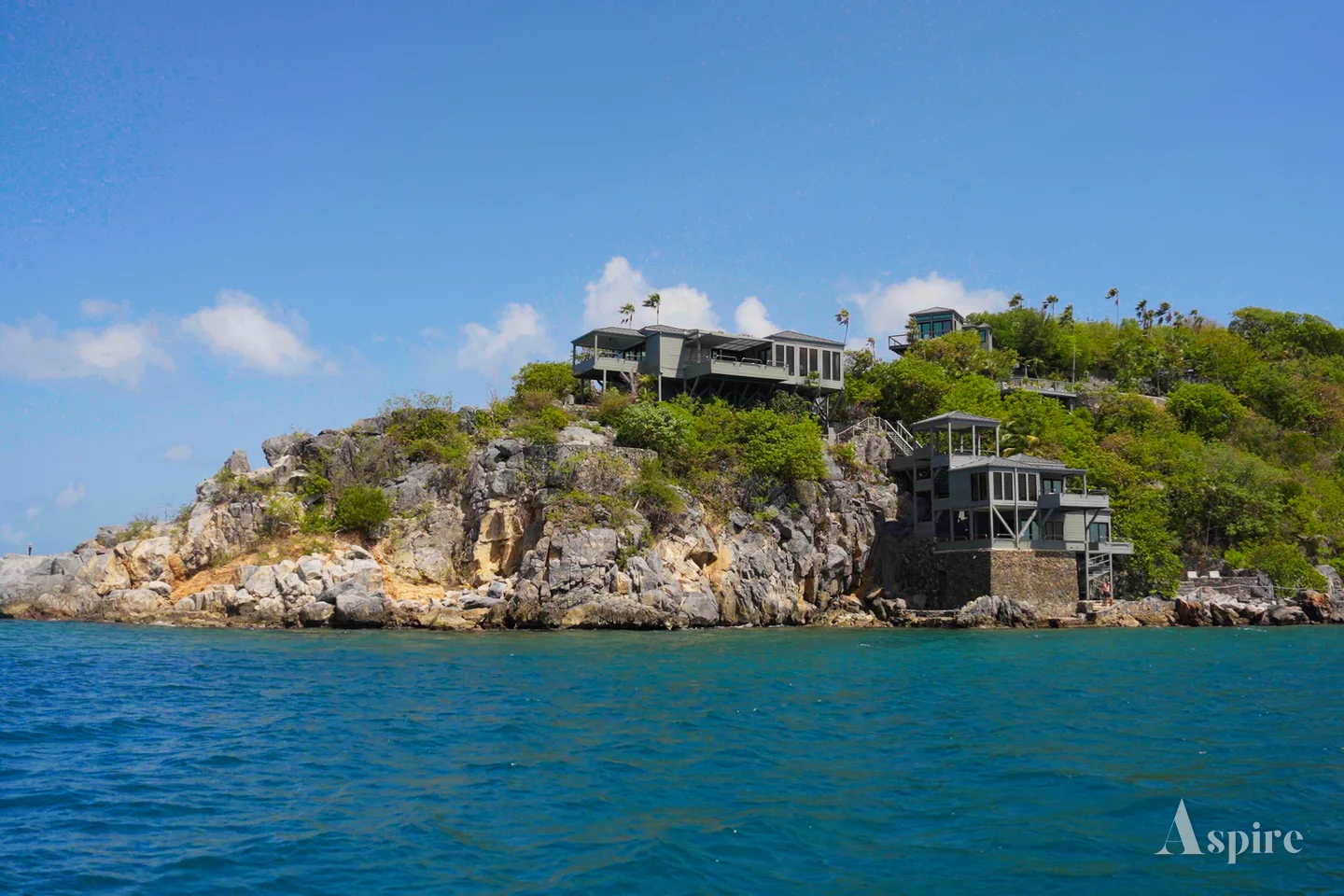 A villa set into a steep wooded coastline seen from the water