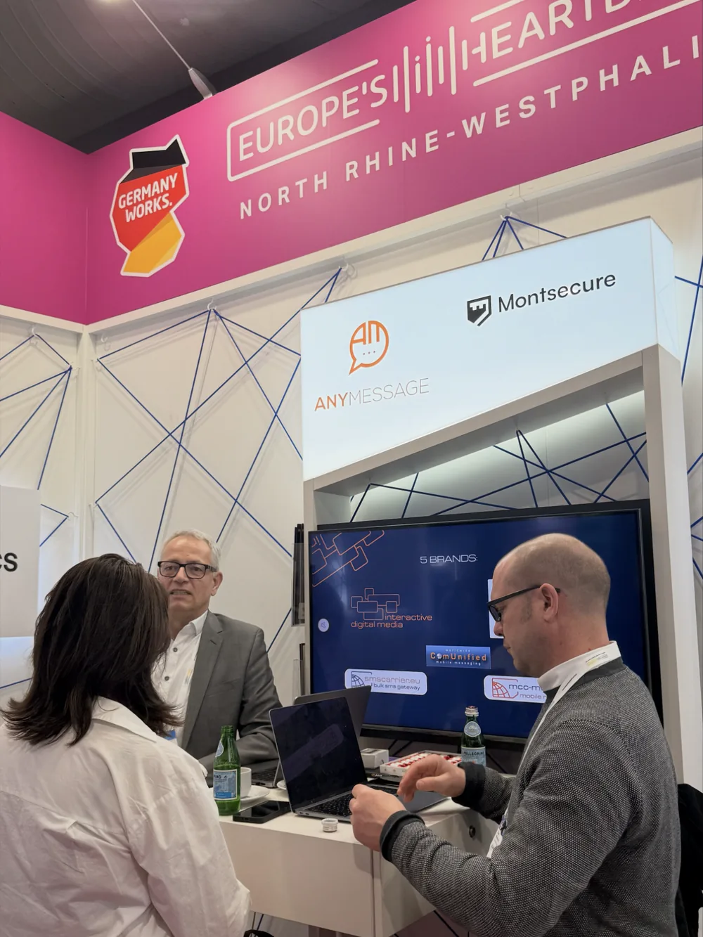 Two people talking at a trade stand with product screens behind them