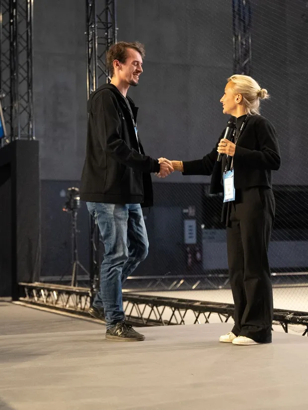 Two people shaking hands on a stage at an event