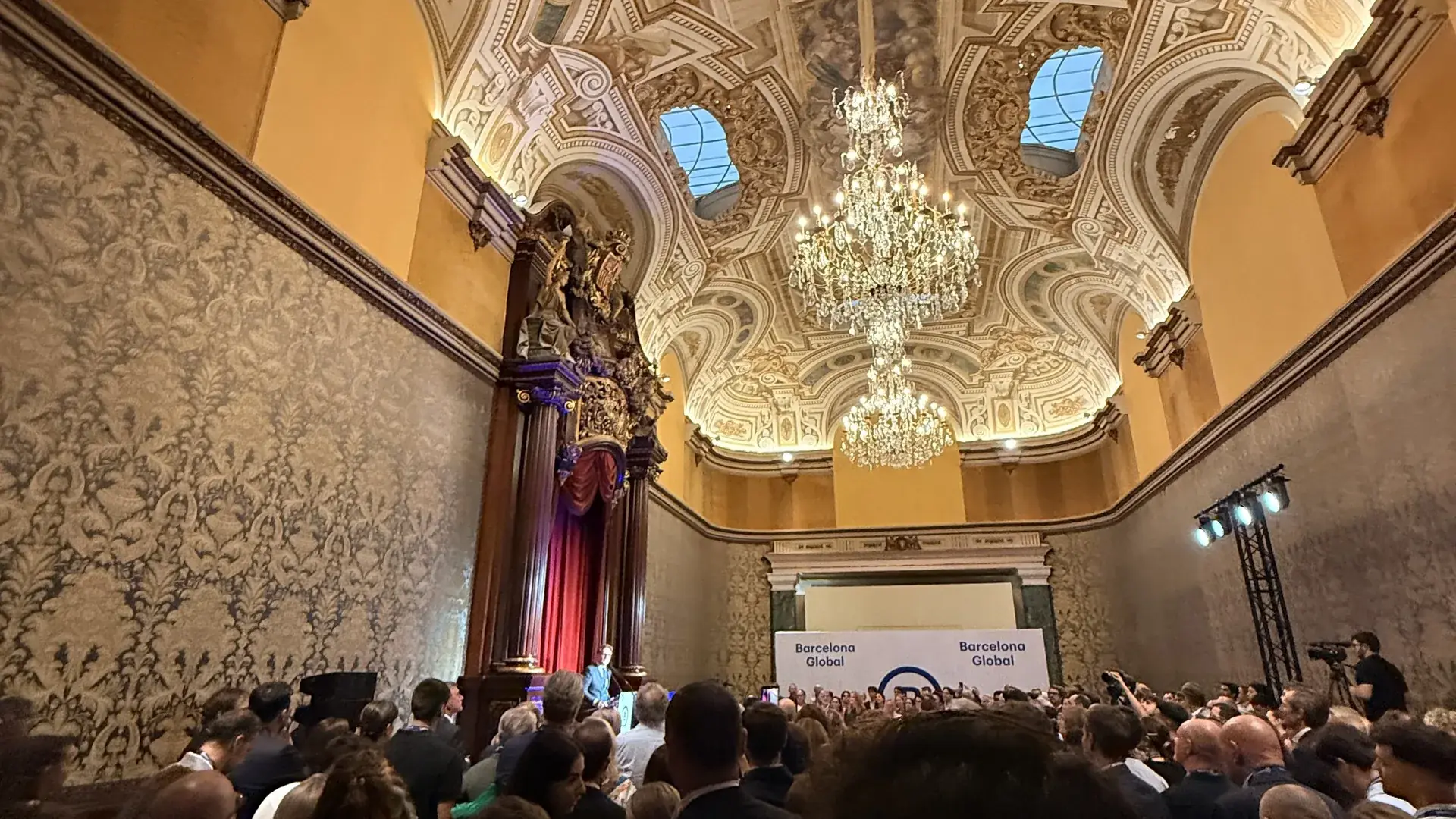 A packed auditorium at a Barcelona Global event, under the hall's ornate ceiling
