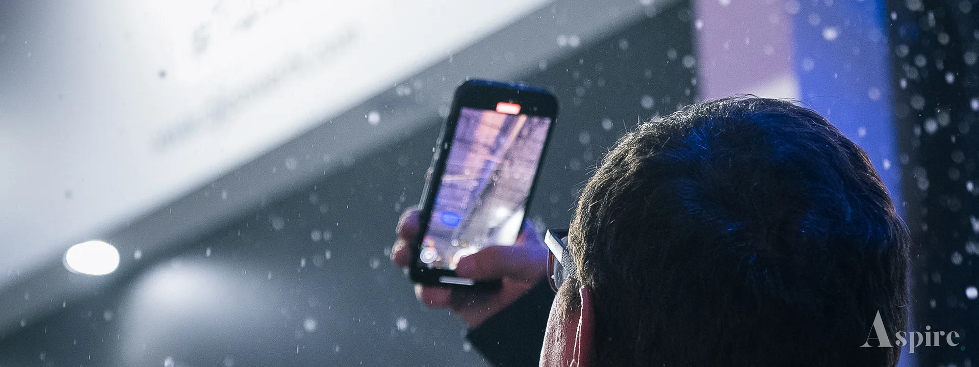 Someone filming a lit display on a phone at an exhibition