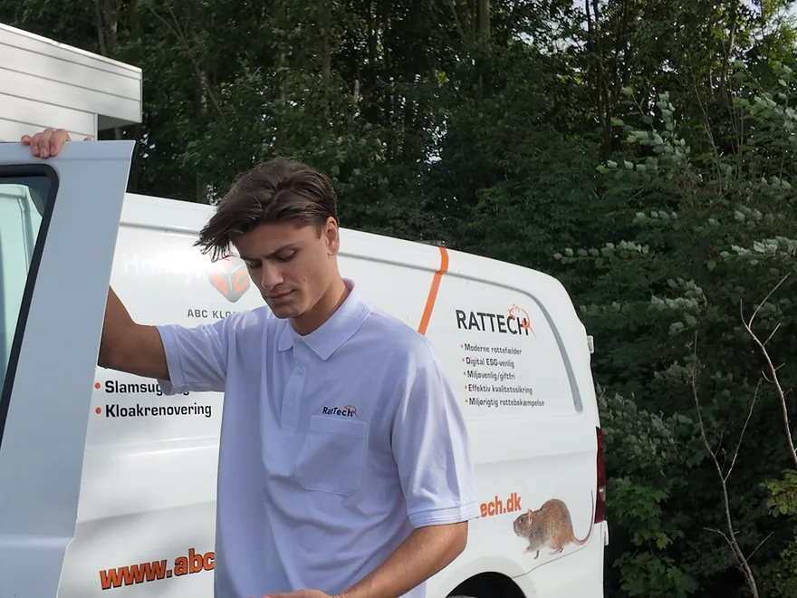 A RatTech technician beside a branded service van